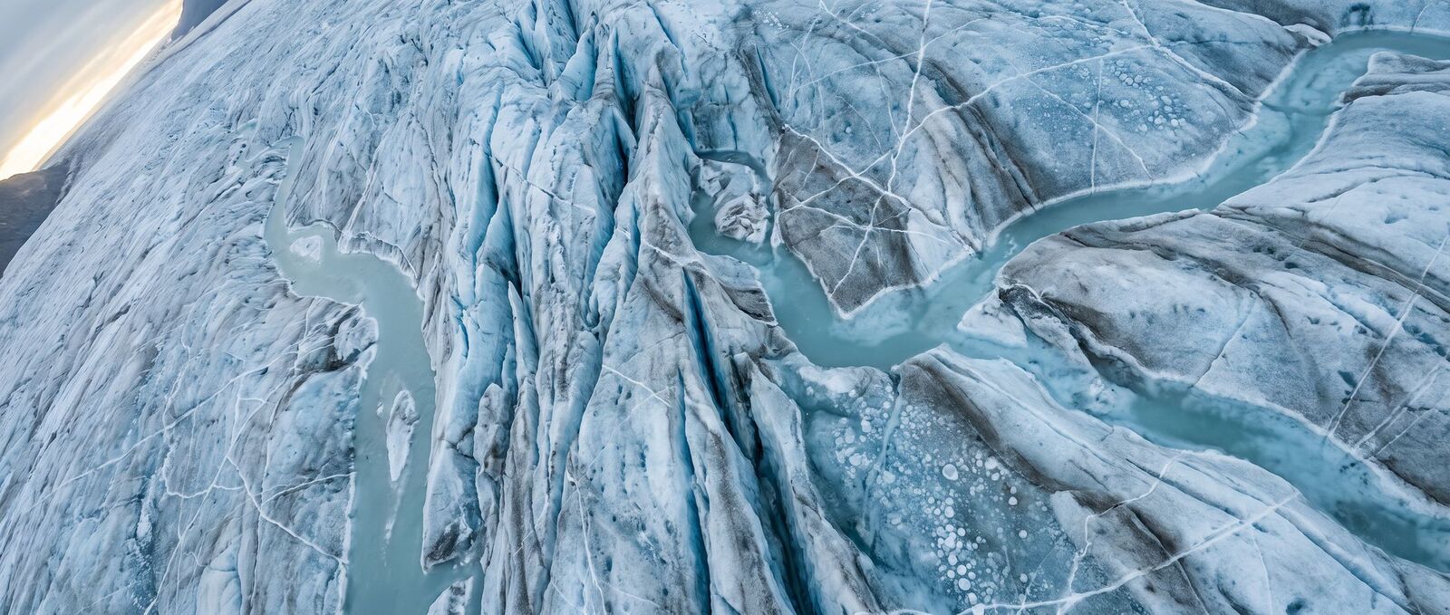 Glacial ice with deep blue crevasse lanes and pale turquoise meltwater